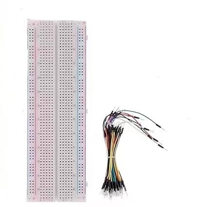 Longue breadboard blanche sans soudure avec des lignes de rail rouges et bleues sur les deux bords, à côté d’un faisceau de fils de connexion souples